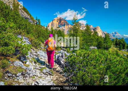 Cheerful healthy active woman hiker with colorful backpack and mountain equipment walking on the mountain path, Dolomites, Italy, Europe Stock Photo