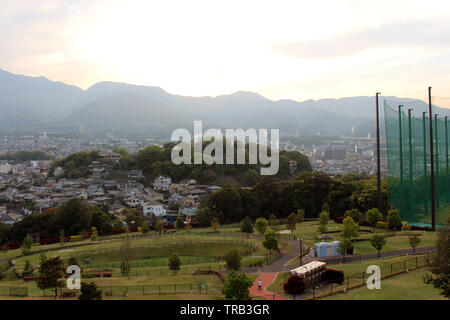 The landscape of Beppu in Oita and golf range as seen from a hill in sunset. Including the steam! Stock Photo