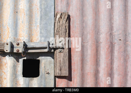 A close up of a slide bolt lock on the door of an old galvanised iron shed or barn on a farm in northwest New South Wales, Australia Stock Photo
