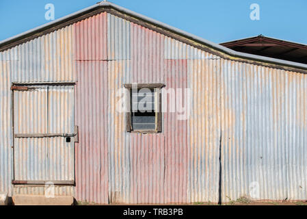 The side view of an old galvanised iron shed or barn on a farm in northwest New South Wales, Australia including a small louvered window Stock Photo