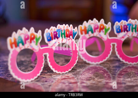 Pink goggles / specs made of cardboard / paper with happy birthday written on top. Stock Photo