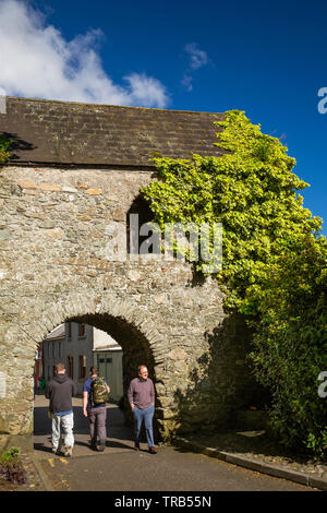 Ireland, Co Louth, Cooley Peninsula, Carlingford, Tholsel Street, visitors, walking through arch of The Tholsel, original Medieval gate in town walls Stock Photo