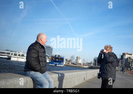 Happy elderly caucasian couple together in the city centre of Amsterdam in spring sunshine enjoying themselves Stock Photo