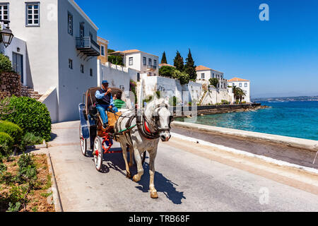 A young couple enjoys a ride by the seaside, with a horse carriage in Spetses near Athens Stock Photo