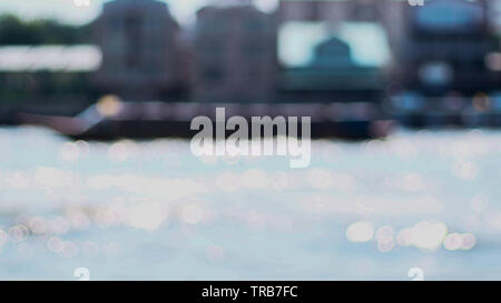 Blurred Bangkok city at Chao Phraya river bokeh reflection of water background. Stock Photo