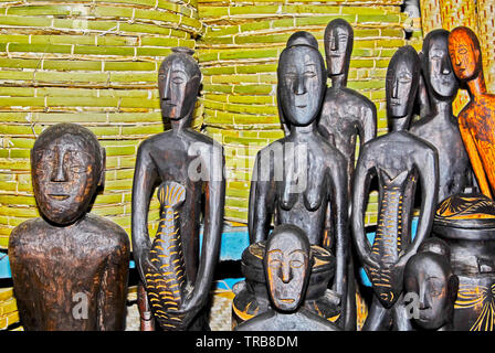 Different sized wooden carved figures standing in front green bamboo background inside a souvenir shop in Puerto Princesa City, Palawan, Philippines Stock Photo