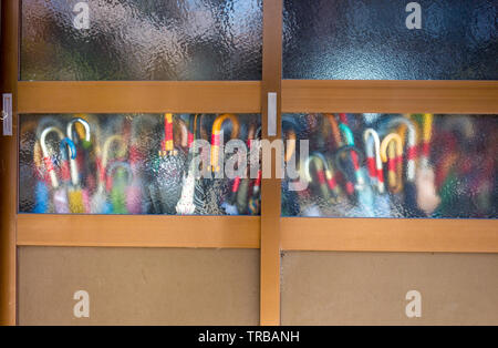Colored umbrellas seen through frosted glass in door, city of Kanazawa, Ishikawa Prefecture, Western Japan. Stock Photo