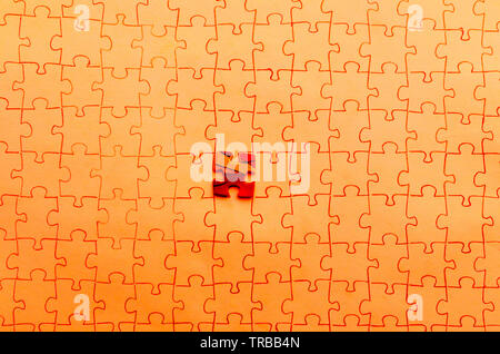 Assembled puzzle on red background, highlight one red cells of puzzle. Stock Photo