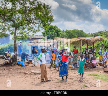 a landscape showing Malawian church members preparing food under grass roofed shelters in Nsanje Stock Photo