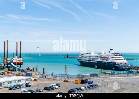 Daytime, large passenger cruise ship docked by small jetty in the sunshine. The luxury Cruise Ship, 'Silver Cloud', operated by private cruise line, 'Silversea Cruises', docked at a mooring outside of Ramsgate Harbour. The Ship has nine decks and carries 300 passengers with a crew of 220. Stock Photo