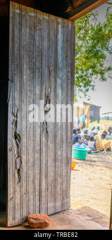 a wooden door of a house in a village of Malawi propped open by a home made brick Stock Photo