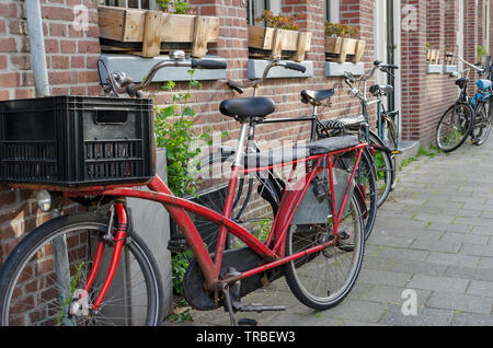 Old long Red vintage bike with two seats more behind the driver and big plastic box in front of him. Street view in Amsterdam, Netherlands. Stock Photo