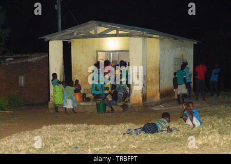 a maize mill in operation at night time in a Malawian village thanks to the provision of electricity Stock Photo