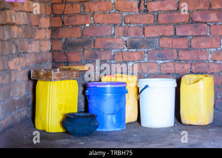 plastic containers recycled so that they can be used to store water, maize flour and food in a house in a Malawian village Stock Photo