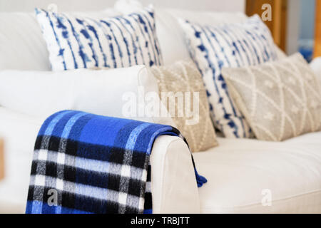 Living room interior with fabric material white colour sofa blue beige elements cushions and plaid close up image no people, modern cozy flat Stock Photo
