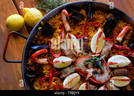 Delicious Spanish seafood paella, view from above. Cooked with sturgeon halibut fillet, peeled shrimps squids, mussels lobster decorated with lemon to Stock Photo