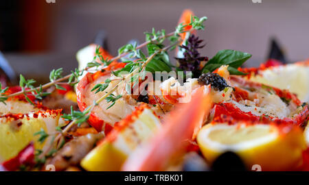 Close up image ripe ingredients of prepared served paella spanish traditional cuisine by country, bright colors. Dish garnished with lemon slices, lob Stock Photo