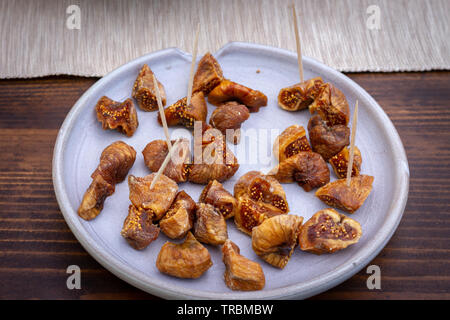 Dried figs in a grey plate on a wooden table. Dried figs are very common in Greece. Stock Photo