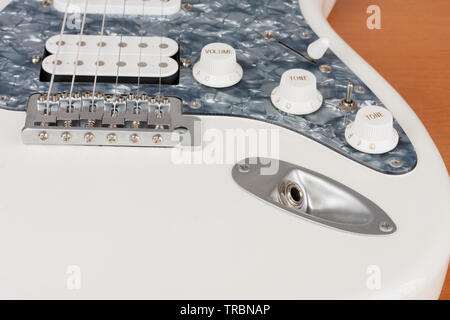 Close up output connector on white electric guitar, studio shoot.  2 x Single Coil and 1 x Humbucking. Black Pearl pickguard Stock Photo