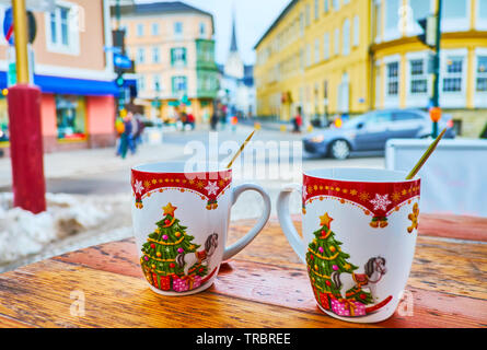 Enjoy hot tea from the Christmas mugs in outdoor cafe with a view on historic townhouses in Pfarrgasse street, Bad Ischl Stock Photo