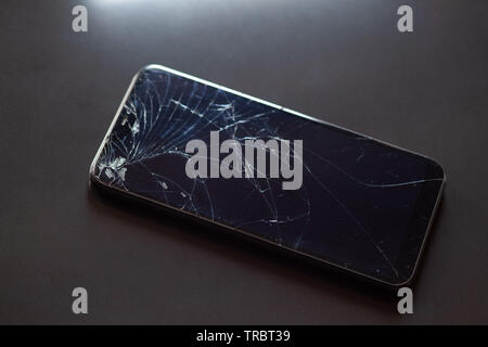 Smartphone with broken touchscreen screen on black desktop Stock Photo