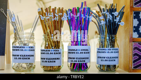 A shelf of colourful steel drinking straws in jars on display in shop, reusable, reduce single use plastic working towards zero waste plastic free Stock Photo