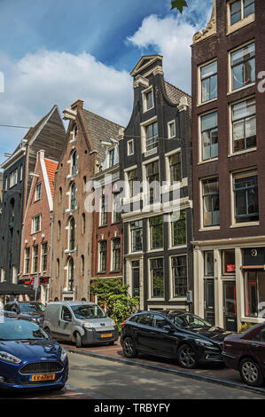 Street with old brick buildings, cars and people passing by in Amsterdam. City with huge cultural activity, canals and bridges in Netherlands. Stock Photo