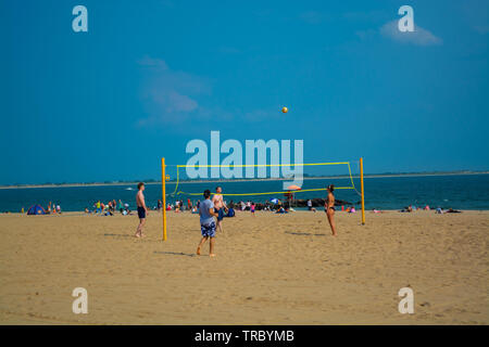 People are playing volleyball on the beach in a warm spring day. Stock Photo