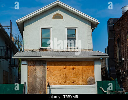 Old house with entrance and first floor windows boarded by the wooden sheets. Stock Photo