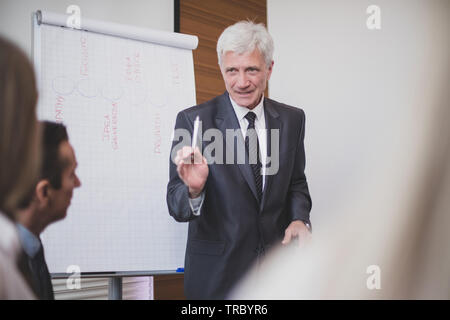 Business man speaking on seminar , whiteboard or flipchart on background Stock Photo