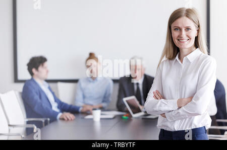 Portrait of beautiful young businessman in front of her team in office Stock Photo