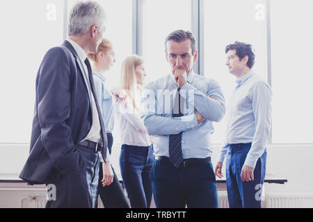 Colleagues having business conversation at meeting in office, serious man thinking holding chin Stock Photo