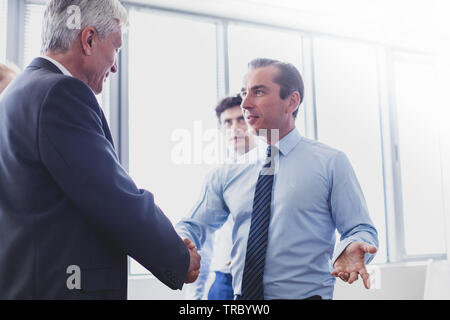 Happy business shaking hands in modern office Stock Photo