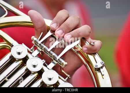 Students hands on the french horn he is learning in California USA real America as he marches in a parade with the school band Stock Photo