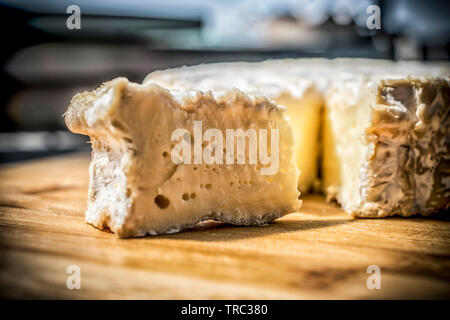 A close-up of a soft French cheese cut on a wooden board Stock Photo