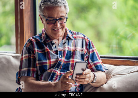 Smiling mature man using smartphone Stock Photo