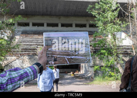 Tour Guide with photo of Avanhard Stadium in the abandoned  city of Pripyat , Chernobyl Exclusion Zone, Ukraine Stock Photo