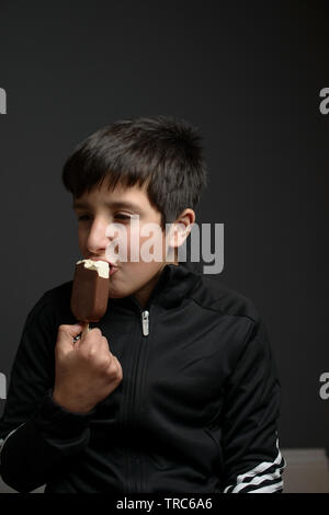 Boy, 12 years old eating ice cream- studio shot Stock Photo
