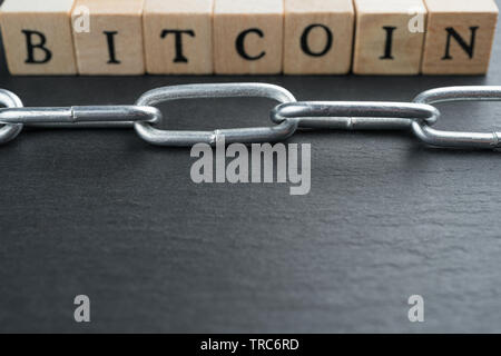 Wooden blocks with "Bitcoin" text and chain. Cryptocurrency blockchain abstract concept. Shallow depth of field. Stock Photo