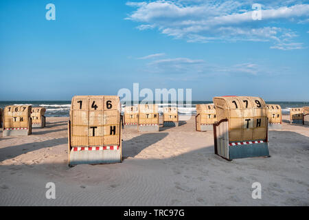 View from a beach onto the Baltic Sea and the backsides of empty beach chairs at sunset Stock Photo