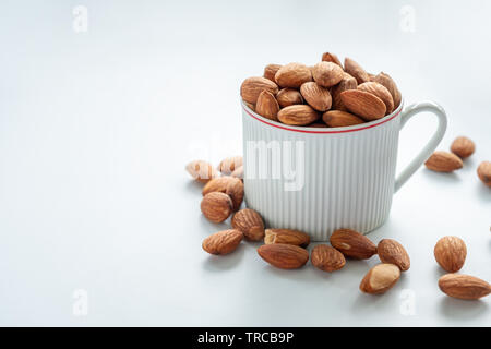 Almonds in white cup on white background Stock Photo
