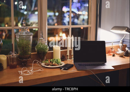 Empty laptop on wooden terraced with flora decoration and food Stock Photo
