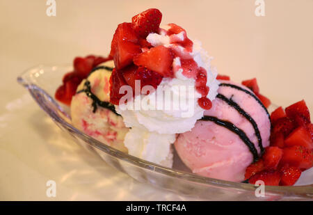 Bowl of delectable ice cream strawberry sundae topped with fresh berries and whipped cream Stock Photo