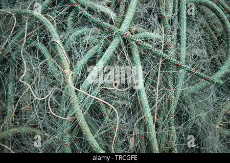Green nylon plastic fishing nets and rope on a beach Stock Photo