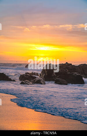 Waves moving on shore as the sunsets on the horizon along famous Highway One near Big Sur, California Stock Photo