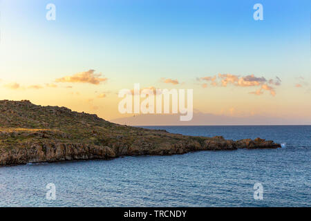 Colorful sunrise over a rocky shoreline in Mykonos, Greece. Stock Photo