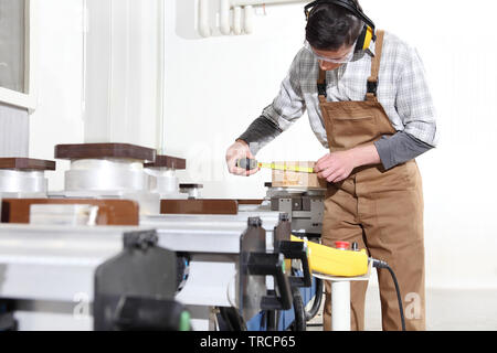 carpenter man works with wooden planks in the joinery, measure with meter, with computer numerical control center, cnc machine,  isolated on a white b Stock Photo