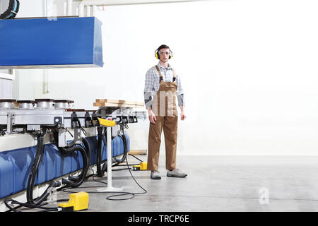 carpenter man works with wooden planks in the joinery, with computer numerical control center, cnc machine,  isolated on a white background Stock Photo