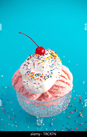 A Strawberry Ice Cream Sundae on a Bright Blue Background with a Cherry on Top Stock Photo