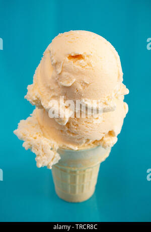 Double Scoop Vanilla Ice Cream Cone on a Blue Background Stock Photo